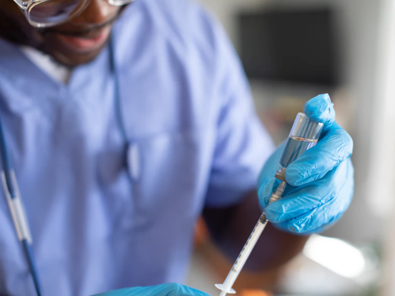 Clinician in a lab coat and gloves preparing equipment