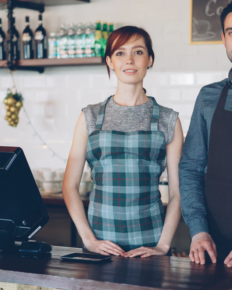 Café staff wearing custom bib aprons behind a service counter